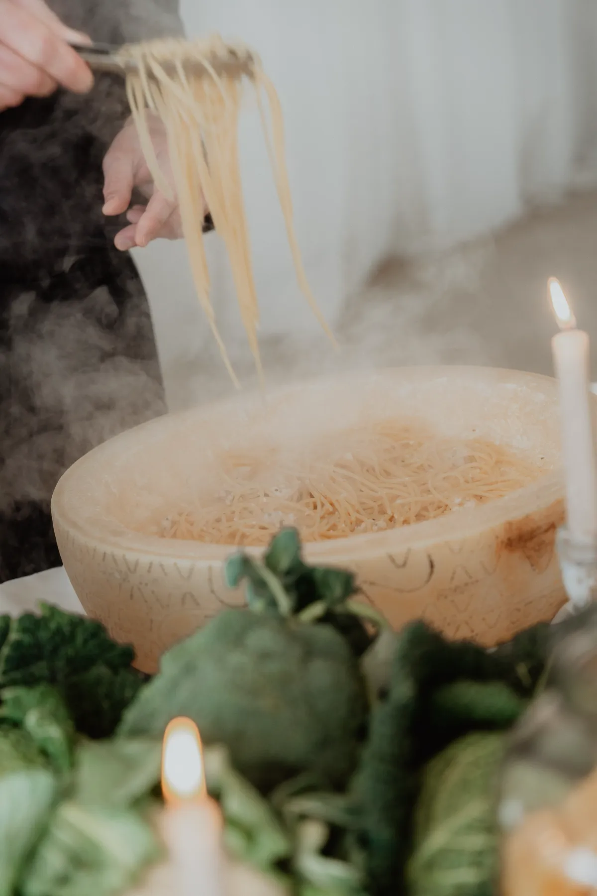 Chef from Catering Majetic preparing authentic pasta alla ruota in a large parmesan wheel during a live cooking wedding station.