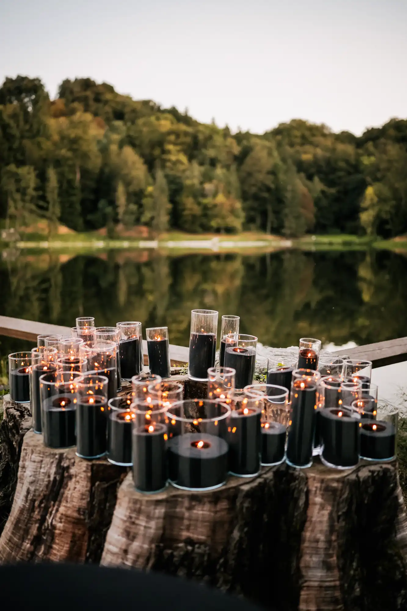 Romantic lakeside wedding decoration with numerous candles on a rustic wooden stump, organized by Catering Majetic in Croatia
