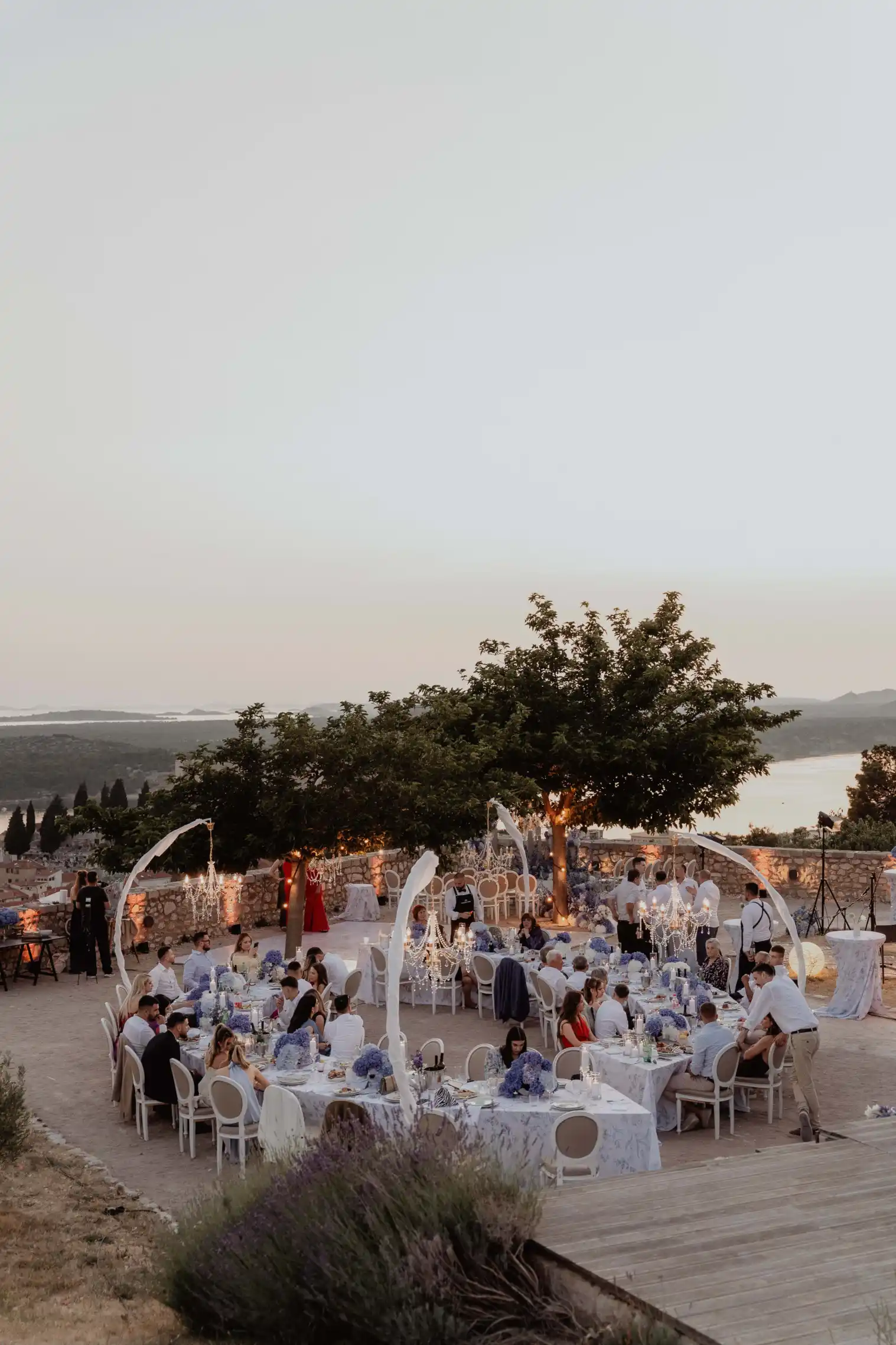 Panoramic view of an outdoor sunset wedding dinner at Barone Fortress in Sibenik, featuring exquisite banquet organization by Catering Majetic.