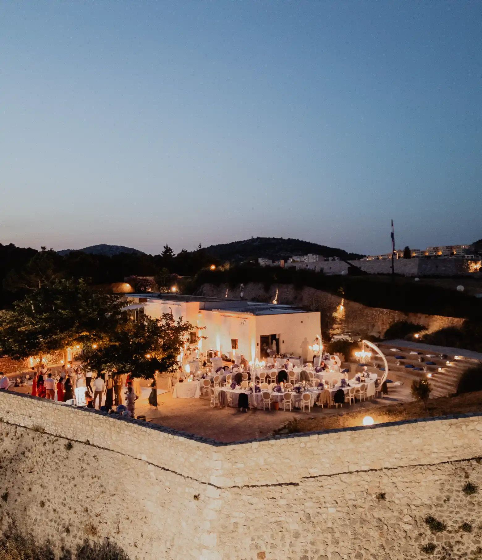 Elegant evening wedding banquet at Barone Fortress in Sibenik with a stunning historic stone wall background.
